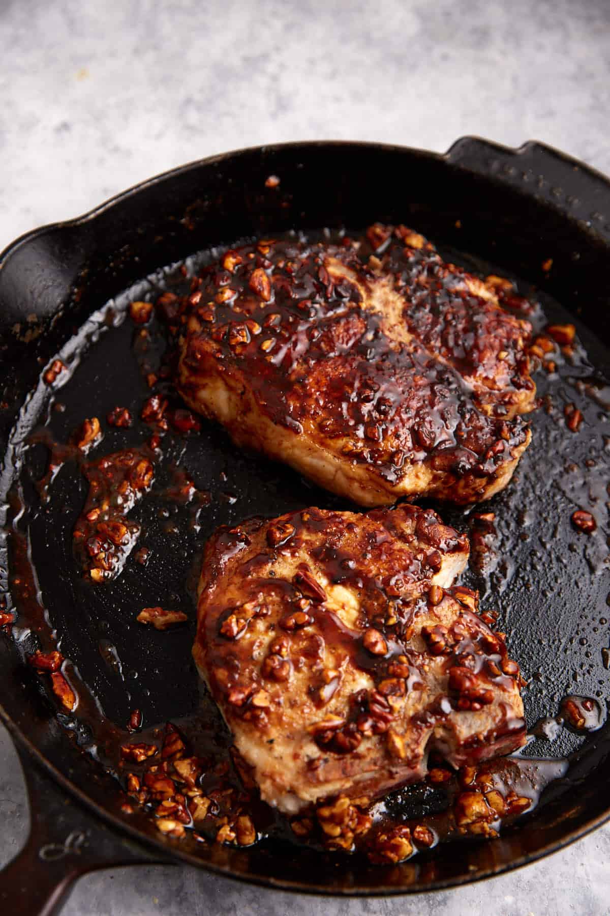 Two pork chops in a skillet.
