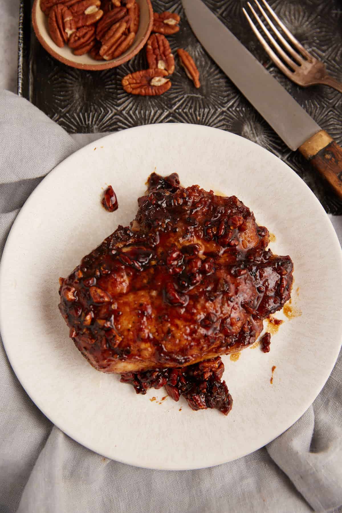 A cooked honey glazed pork chop on a white plate.