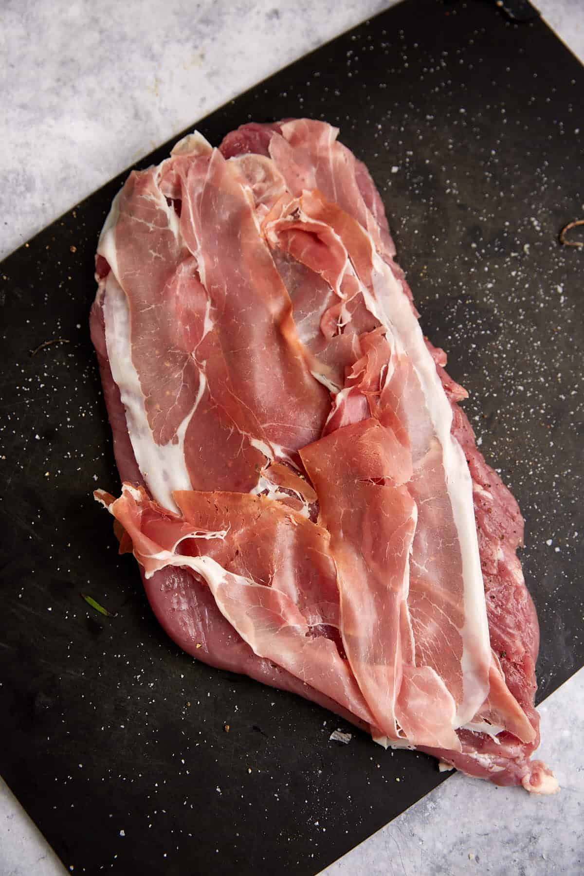 A pork tenderloin with prosciutto on top.