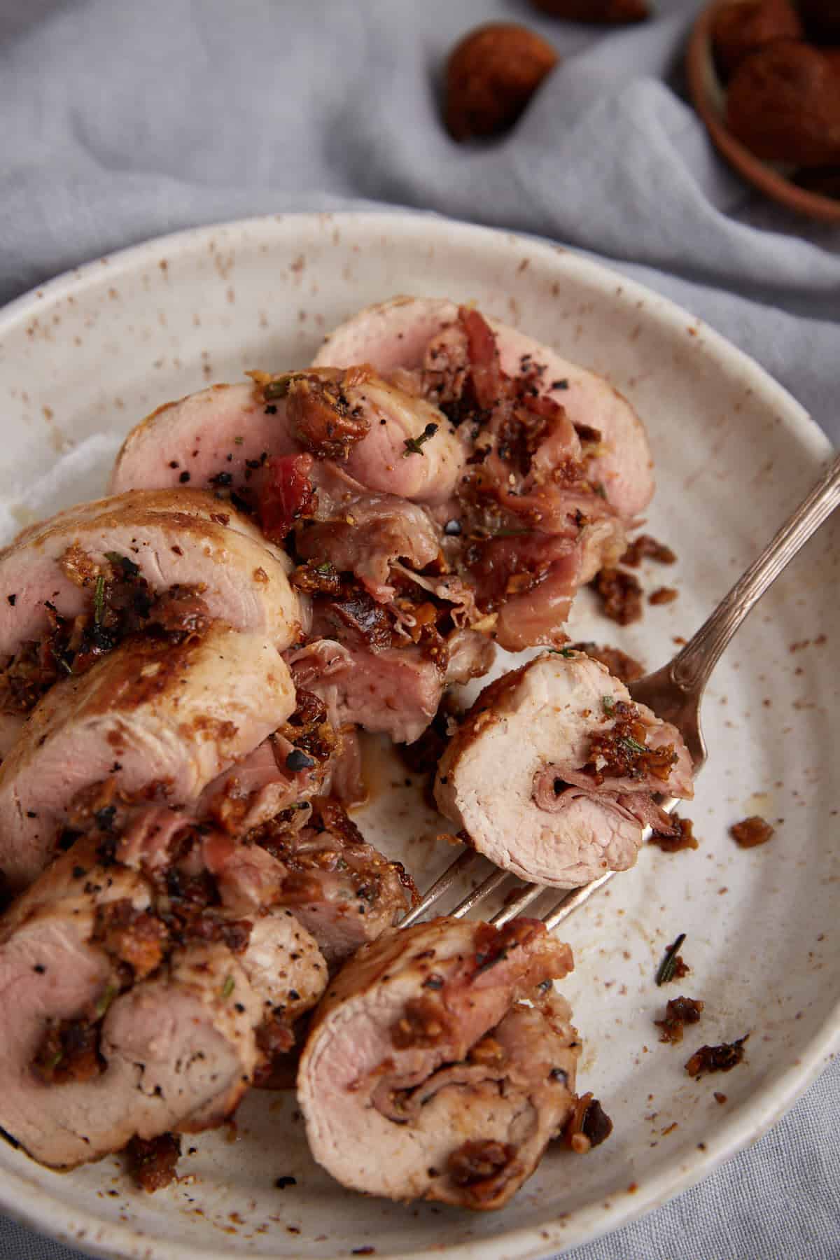 A fork removing a slice of pork tenderloin.