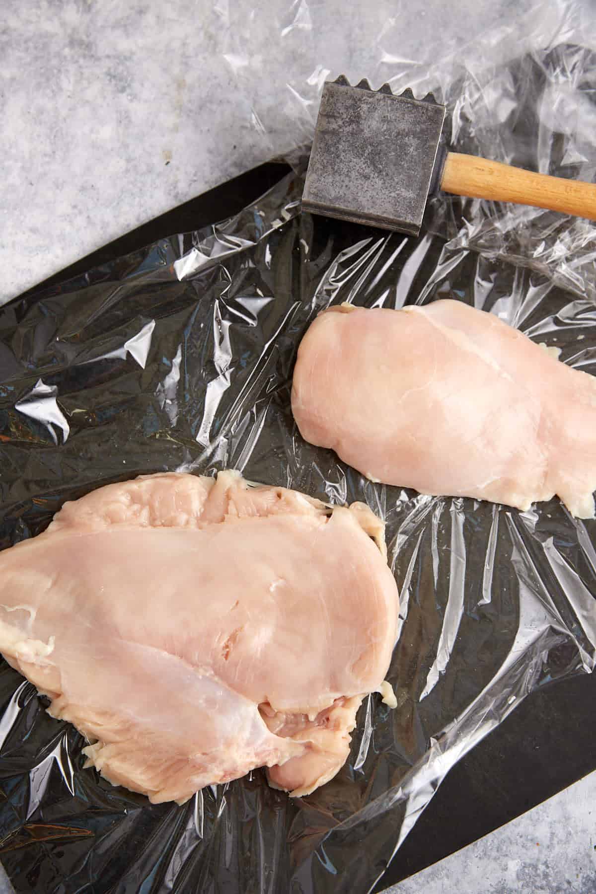 Chicken pounded between plastic wrap.