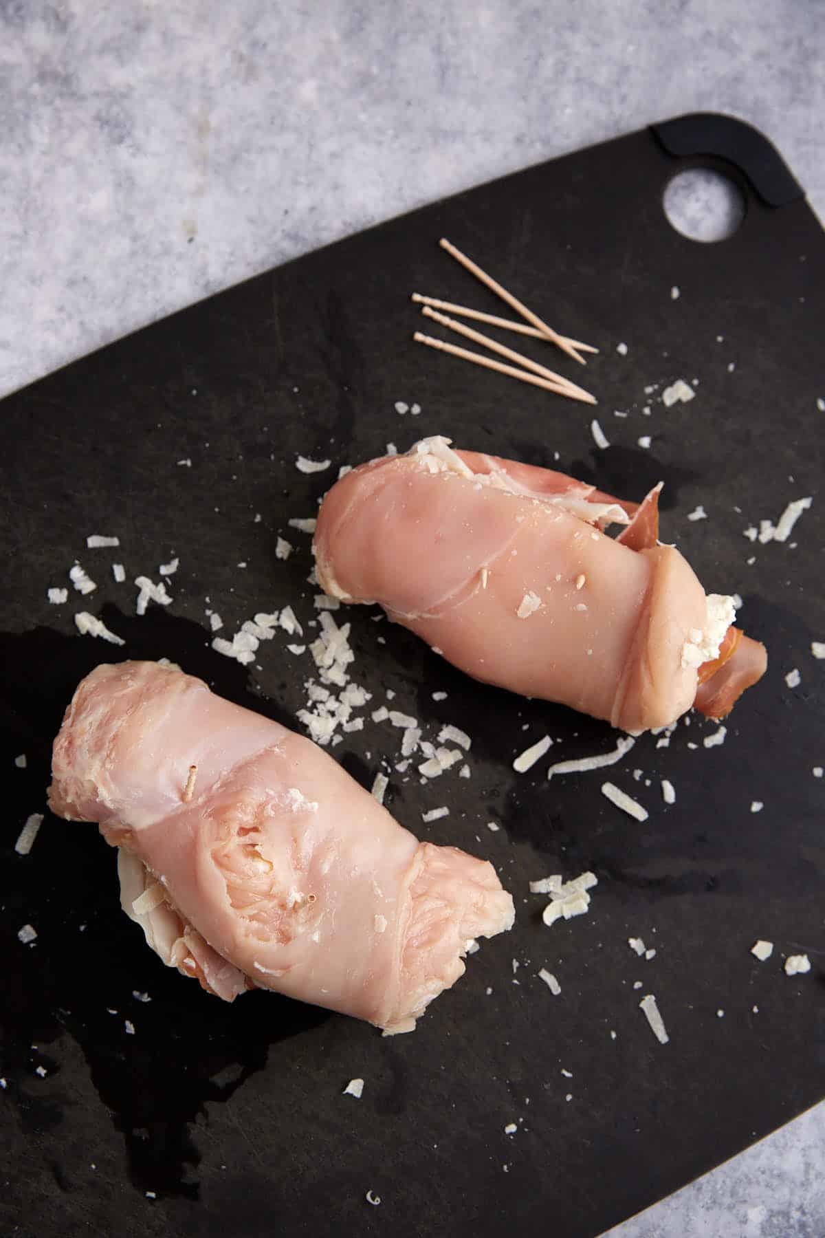 Chicken breasts rolled up on a cutting board.