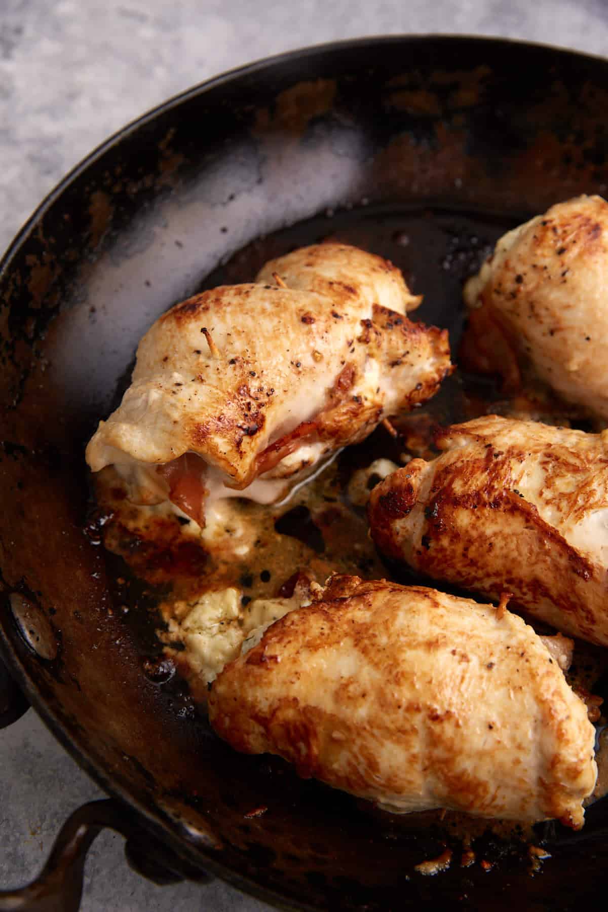 Stuffed chicken breasts baked in a skillet.