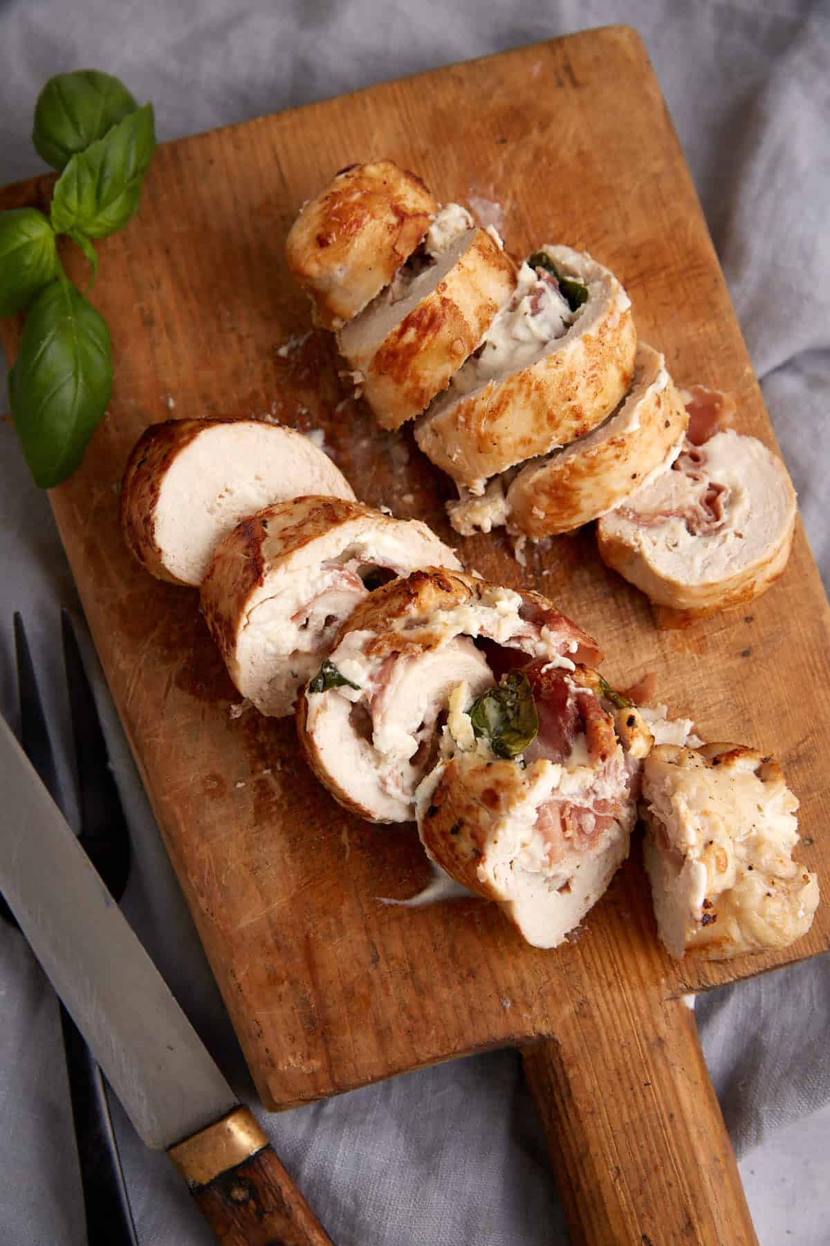 Two chicken breasts sliced on a cutting board.