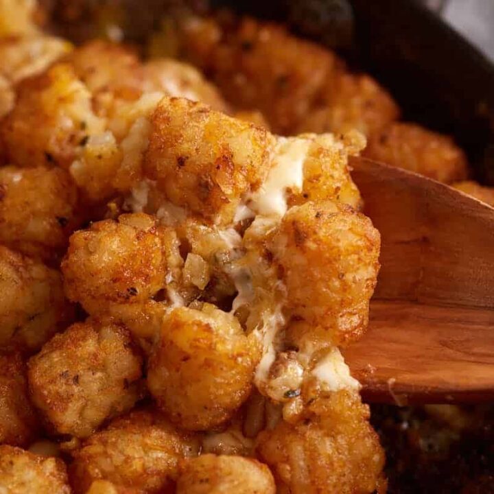 A wooden spoon in a skillet of tater tot casserole.