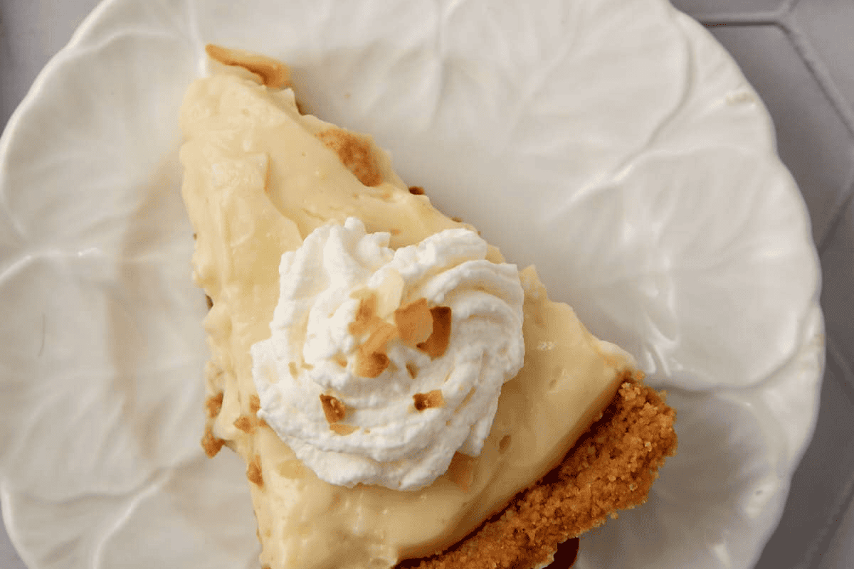 A slice of coconut cream pie with whipped cream and toasted coconut.