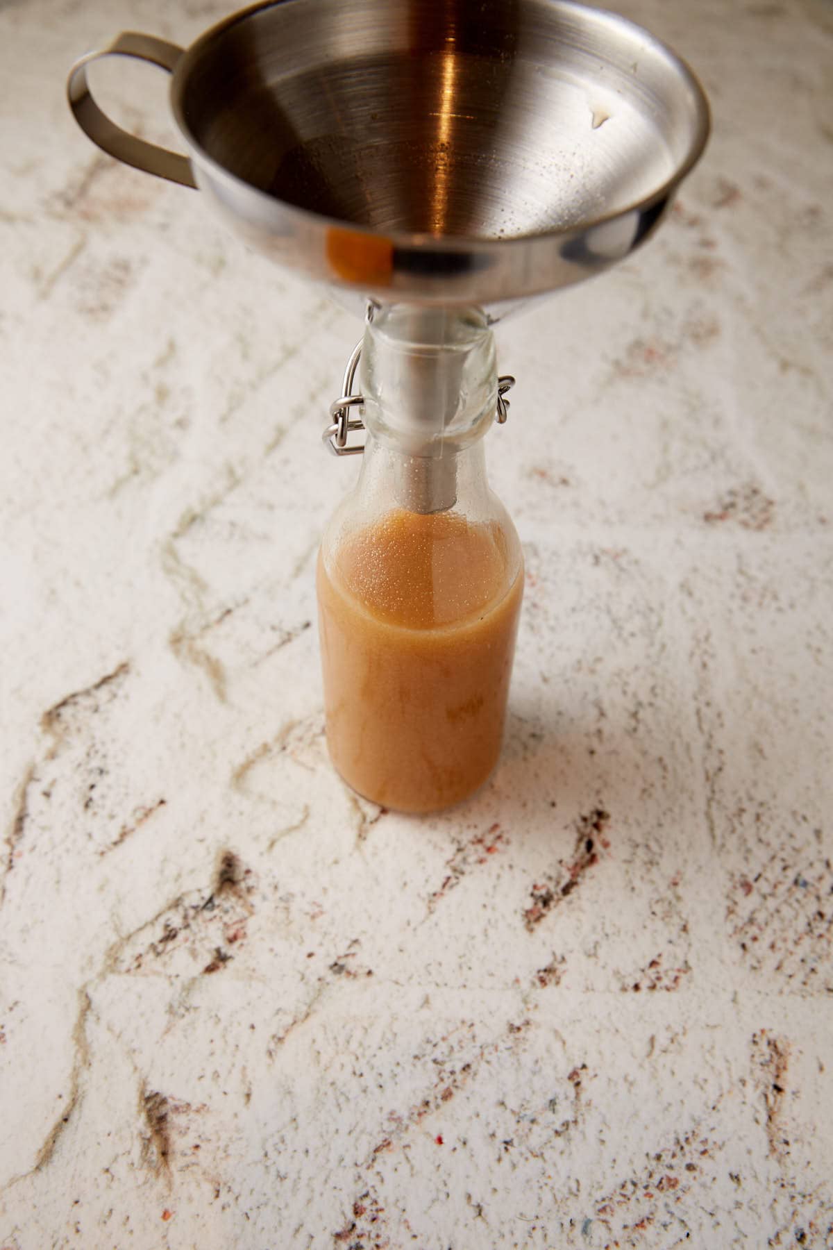 A bottle of carolina sauce with a funnel on top.