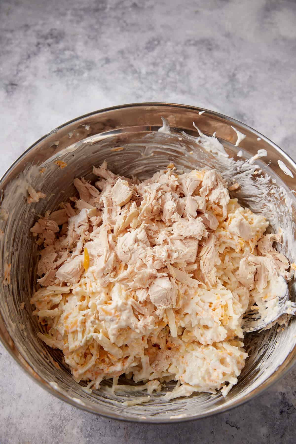 A bowl with chicken, cheese and sauce.