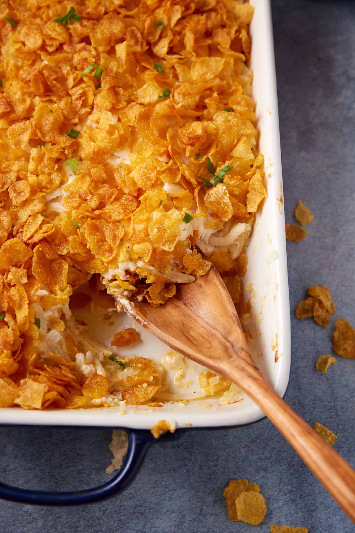 A chicken and hashbrown casserole with a wooden spoon.