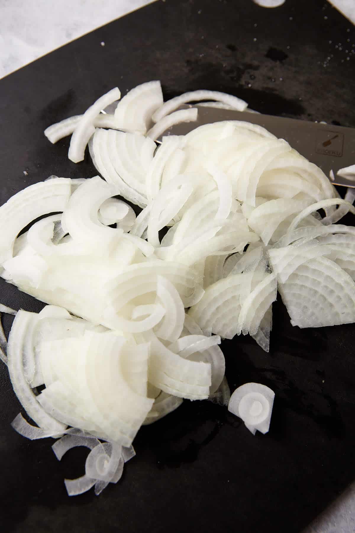 Onions sliced on a cutting board.