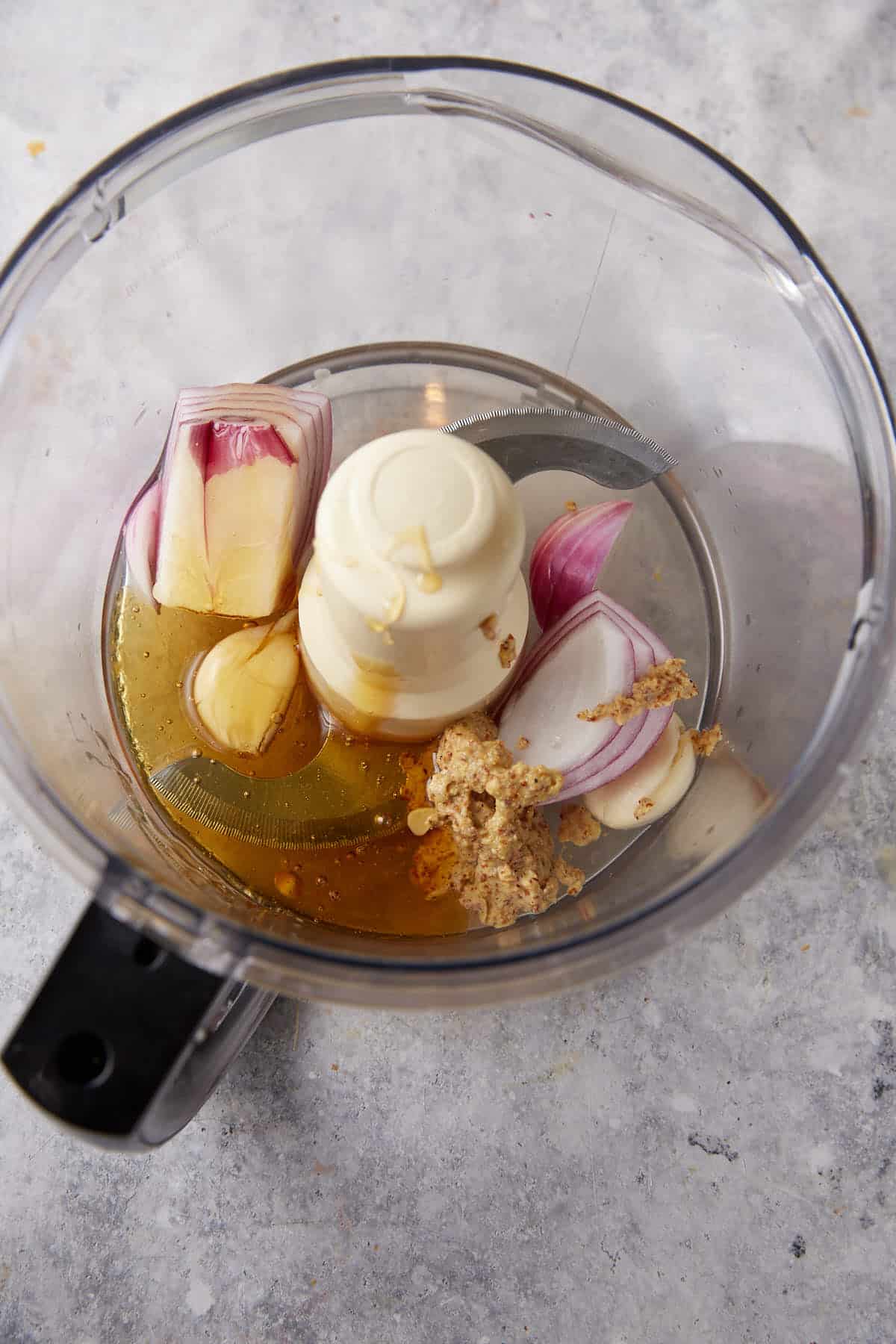 The salad dressing ingredients in the bowl of a food processor.