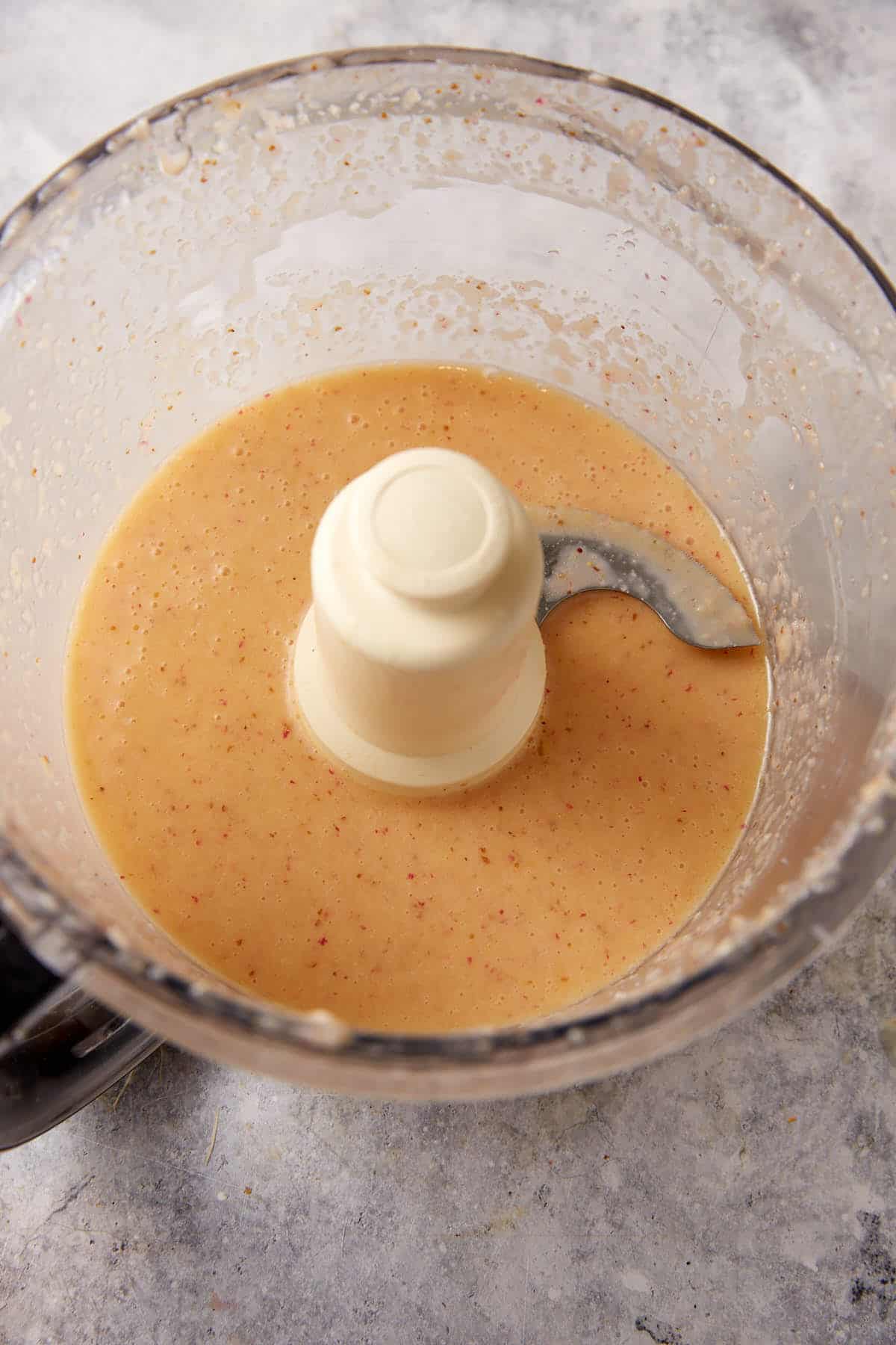 The salad dressing mixed in a food processor.