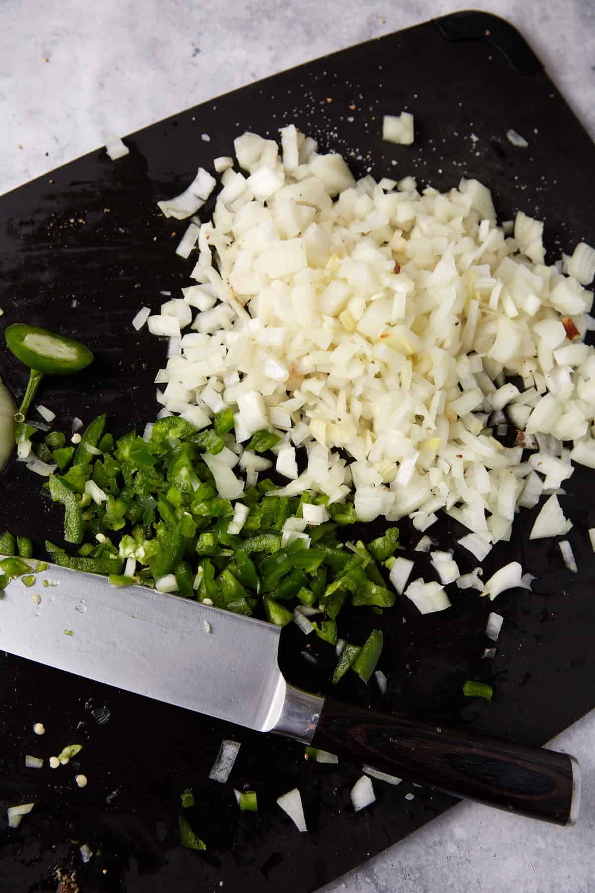 Chopped onions and peppers on a cutting board.