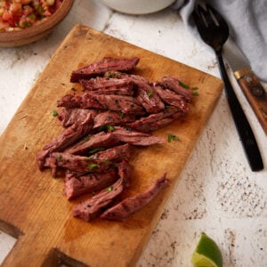 Sliced marinated skirt steak on a cutting board.