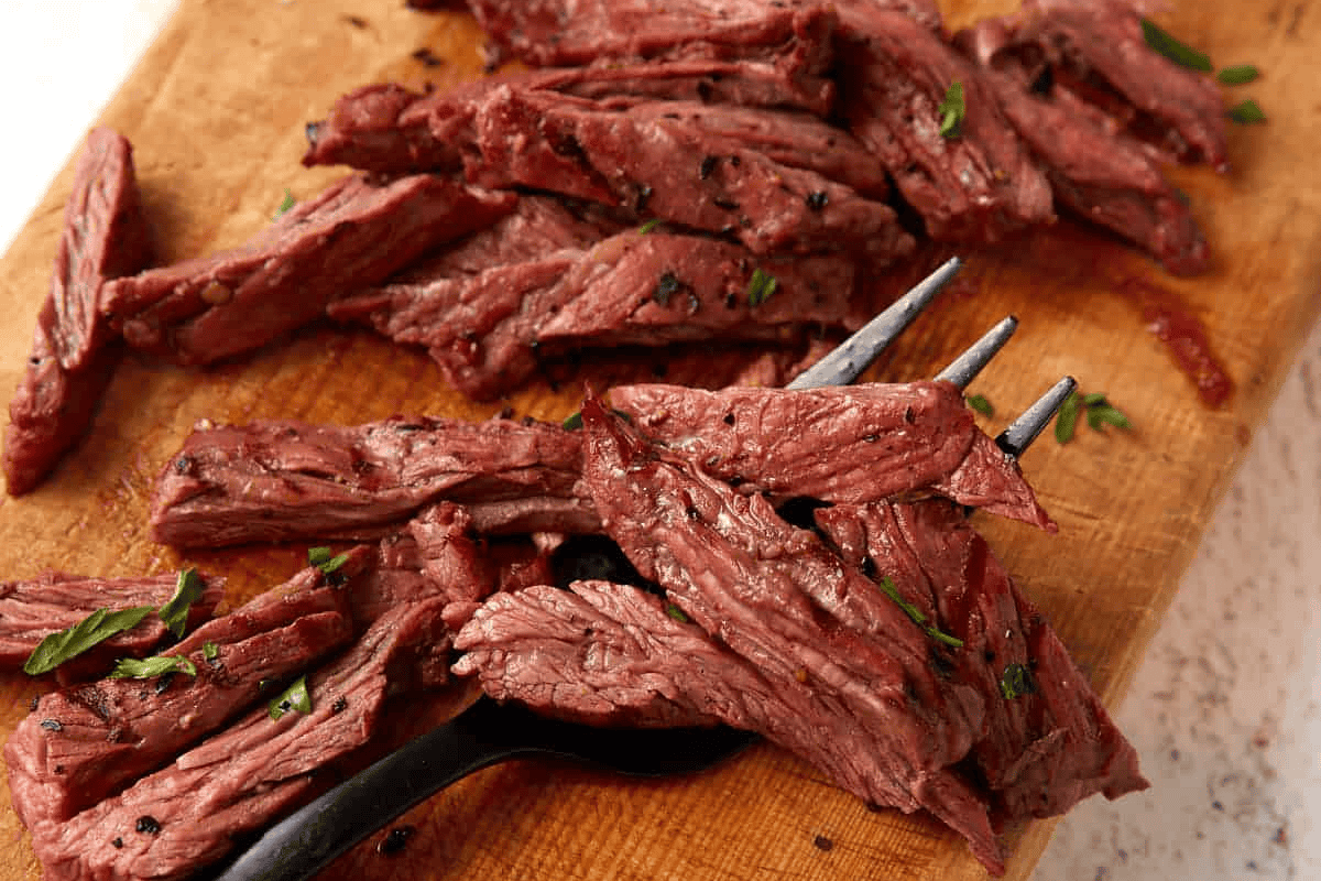 skirt steak sliced on a cutting board.