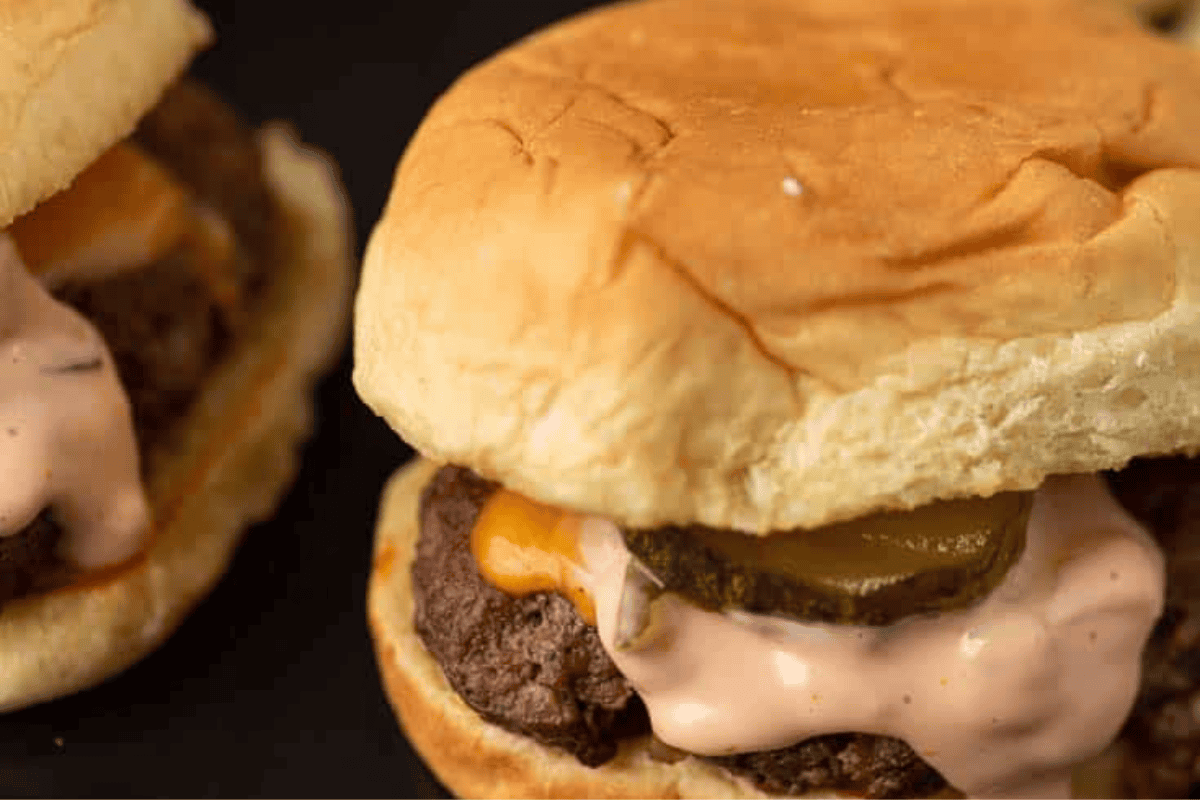 Smash burgers in buns with sauce dripping out.