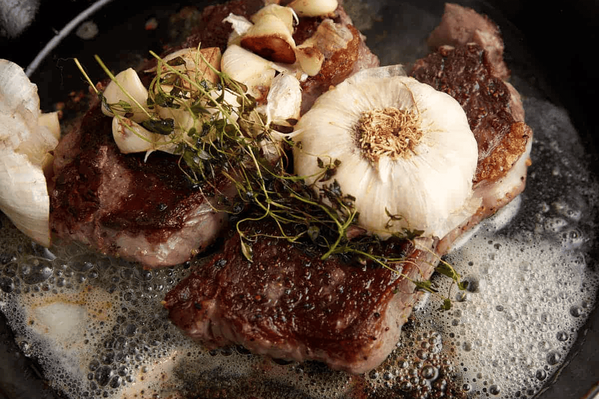 Ribeye Steak in a skillet with butter and garlic.
