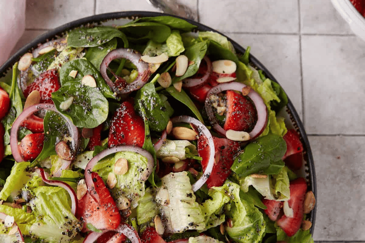 Spinach salad with strawberries in a serving bowl.