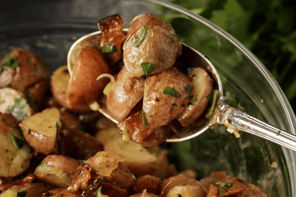 Roasted potato salad in a serving spoon.