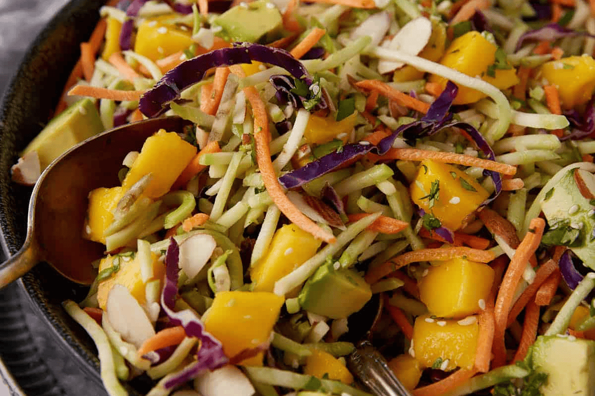 Broccoli salad with mango with a serving spoon.