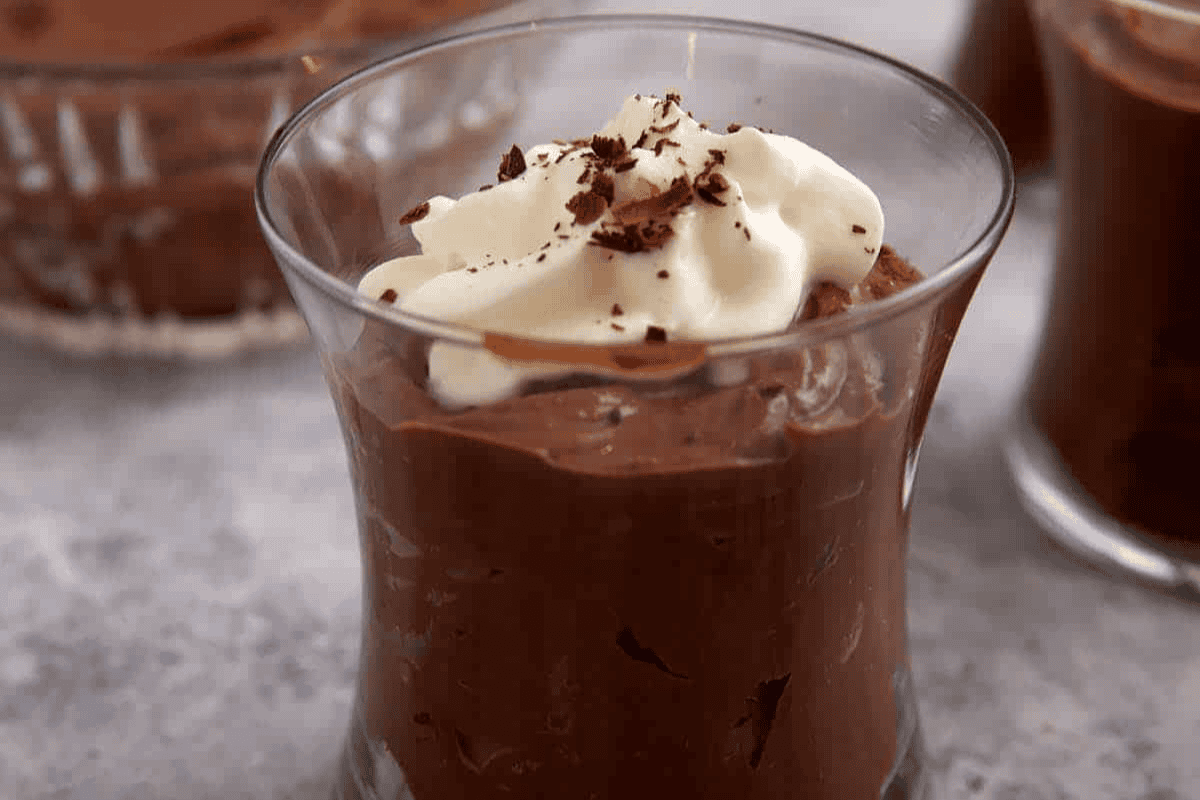 Chocolate pudding topped with whipped cream in a glass.