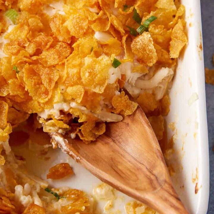 A casserole dish with chicken casserole and a wooden spoon.