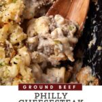 A close-up of a Philly cheesesteak casserole made with ground beef and a gooey cheese sauce. A wooden spoon is shown scooping a portion of the casserole, revealing the cheesy and meaty texture. The image features a text overlay at the bottom that reads "Cheesesteak Casserole Delight.