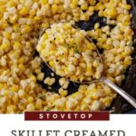 Image shows a close-up of a spoonful of creamy, yellow creamed corn in a skillet. The text on the image reads "STOVETOP Skillet Creamed Corn Homemade." The dish appears to be seasoned and garnished with herbs, capturing the essence of homemade creamed corn.