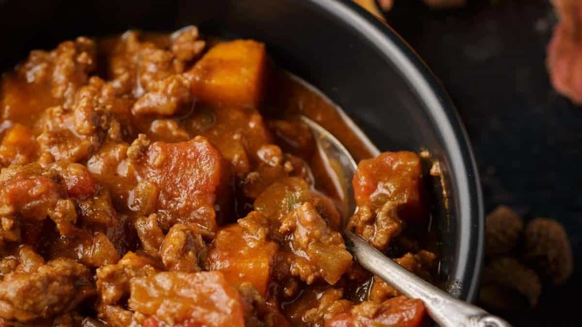 A bowl of chili with sweet potatoes with a spoon