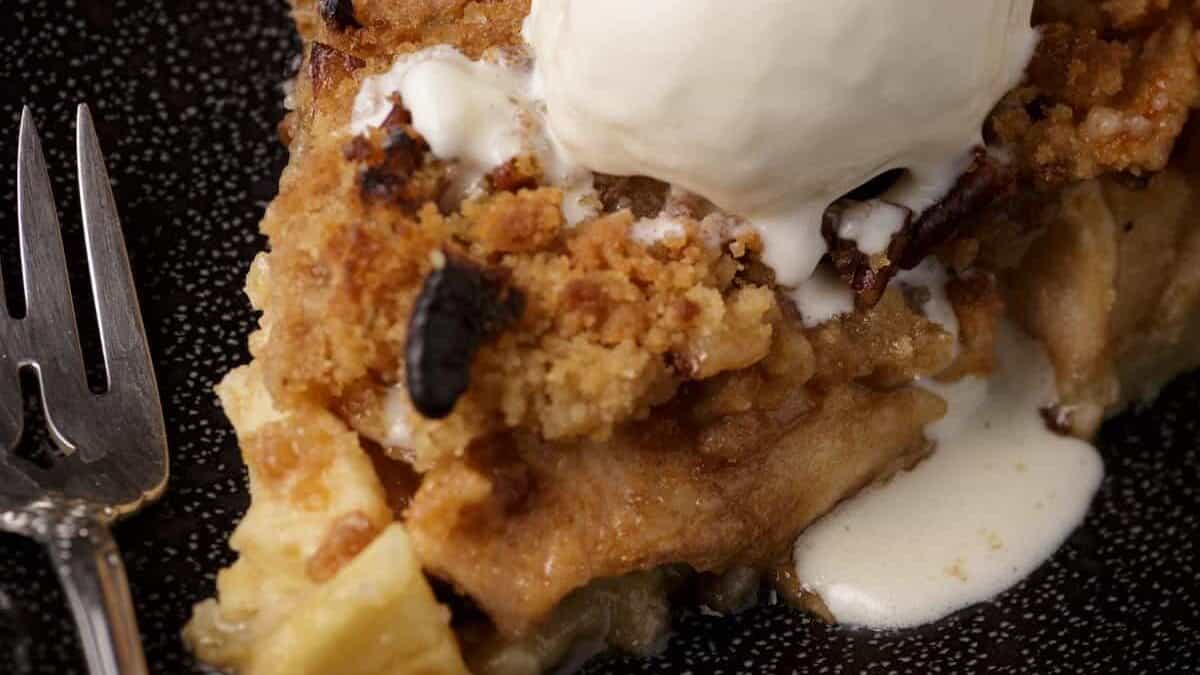 A slice of baked apple pie with ice cream