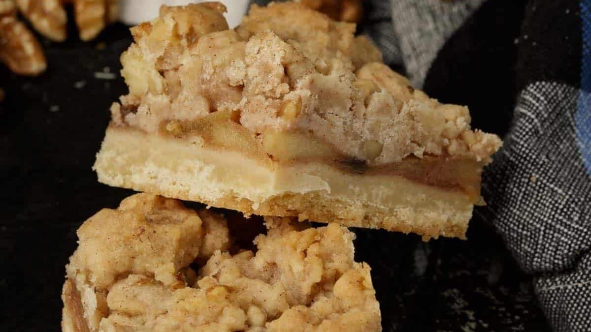 Two apple bars stacked with walnuts in the background.