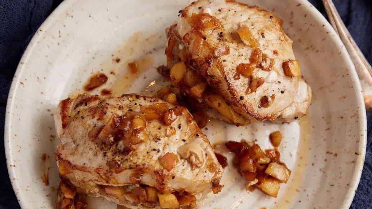 Two apple stuffed pork chops on a plate.
