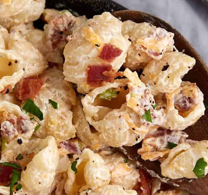Ranch pasta salad in a bowl with a wooden spoon.