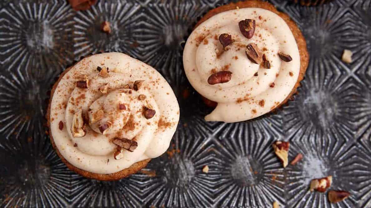 Carrot cake cupcakes frosted on a serving tray.