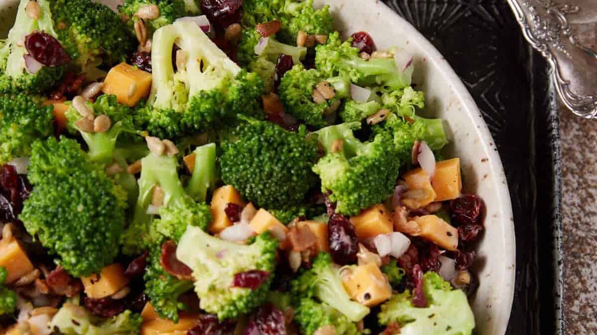 A bowl of broccoli salad on a serving tray.