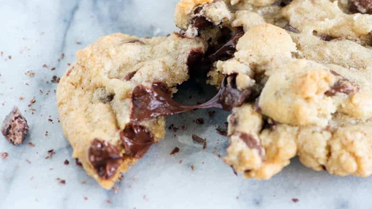 A single chocolate chip cookie with a piece broken off.