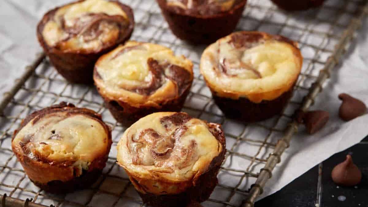 Cheesecake brownie bites on a metal wrack on parchment paper.