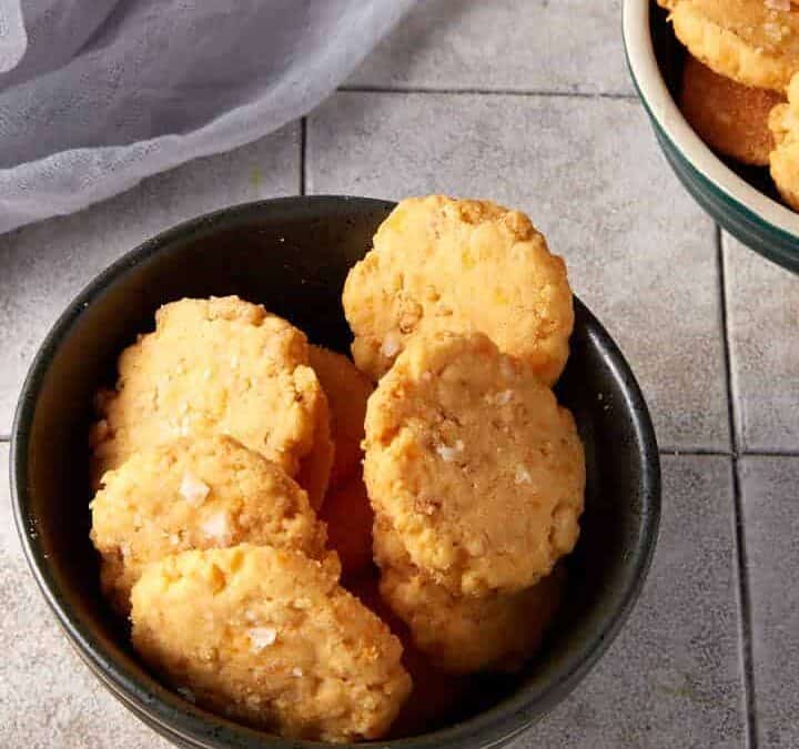 Small bowls of cheese crispies next to a grey linen.