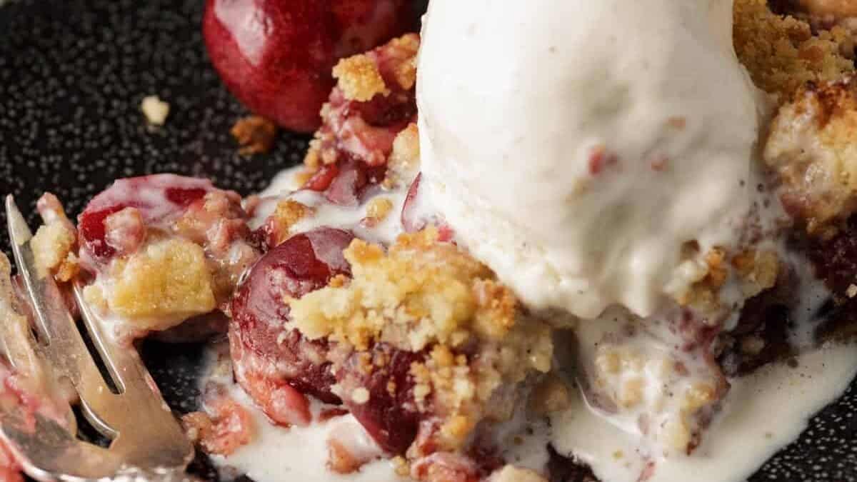 A dish of cherry pie with ice cream melting on the top.