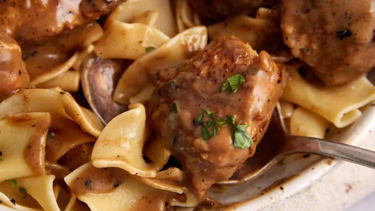 A meatball being taken out of a platter of ground chicken meatballs.