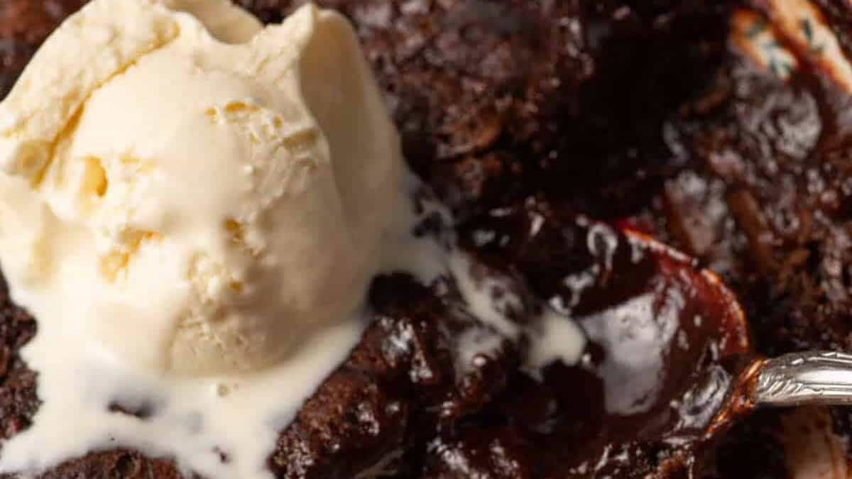 A baking dish of chocolate cobbler topped with ice cream.