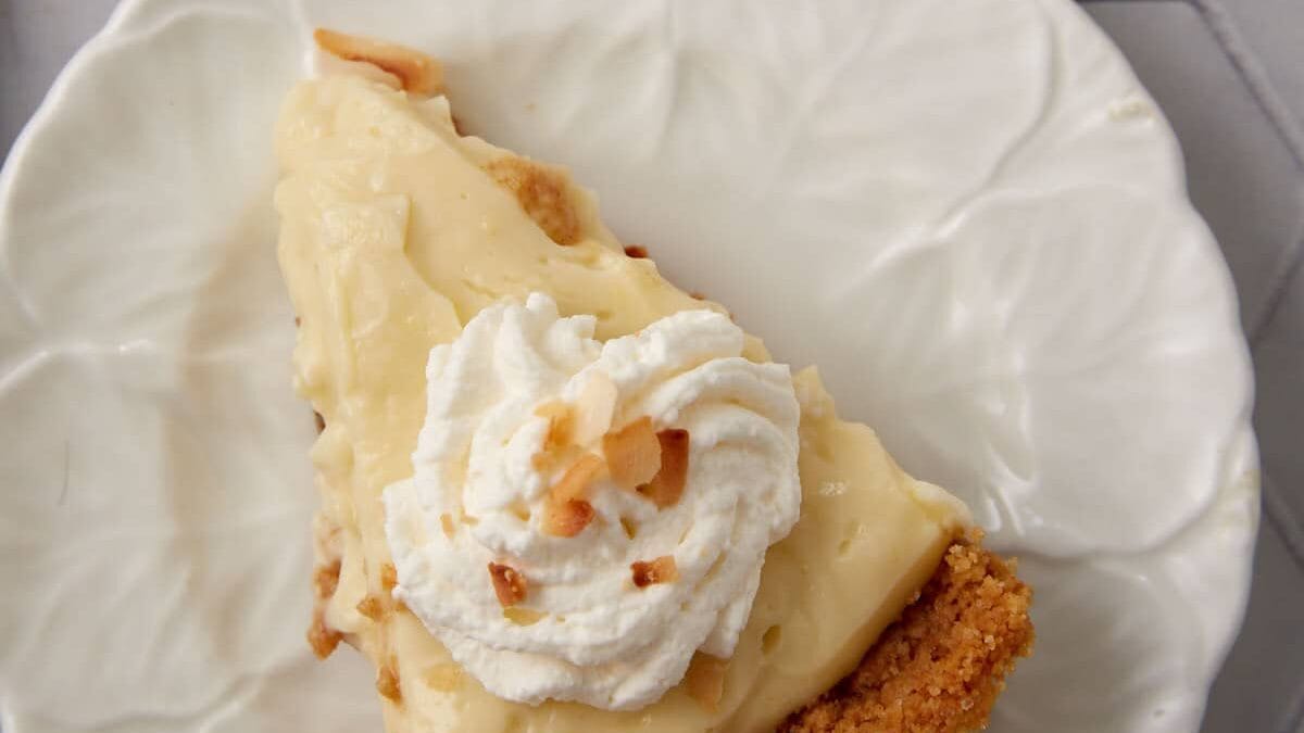 A single slice of coconut cream pie on a white plate.