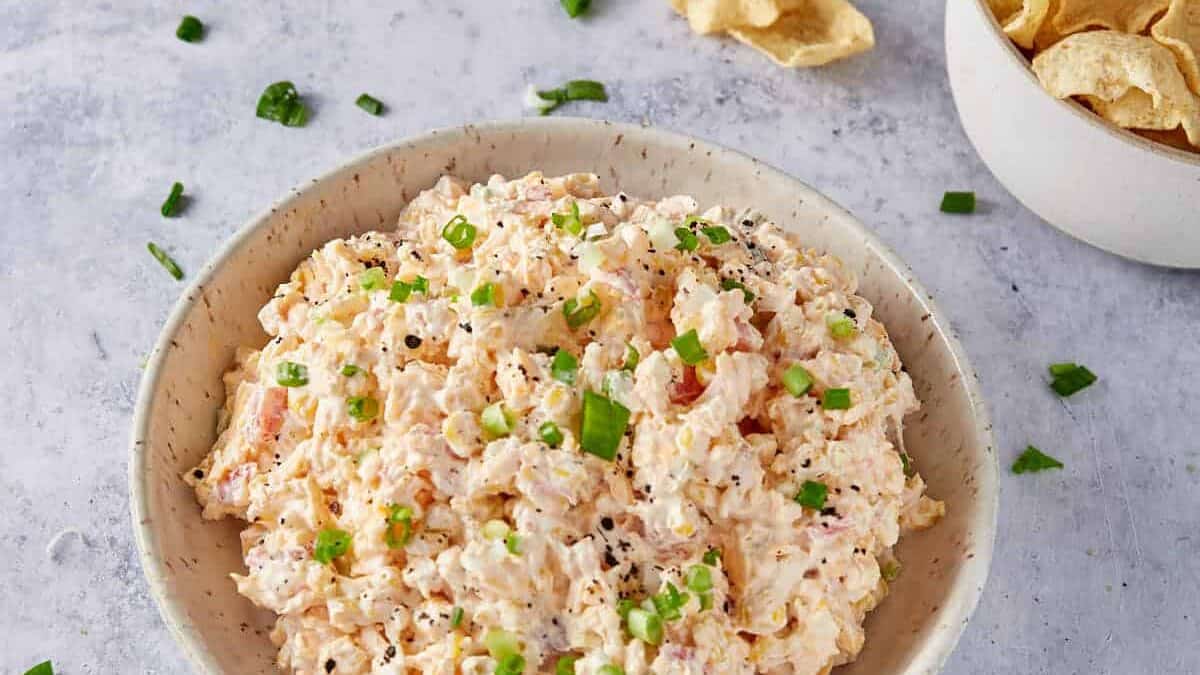 Corn dip in a bowl next to chips.