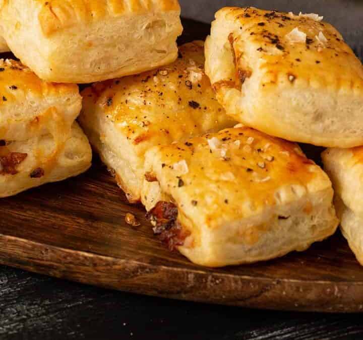 French onion pastry bites on a platter with a glass of wine.