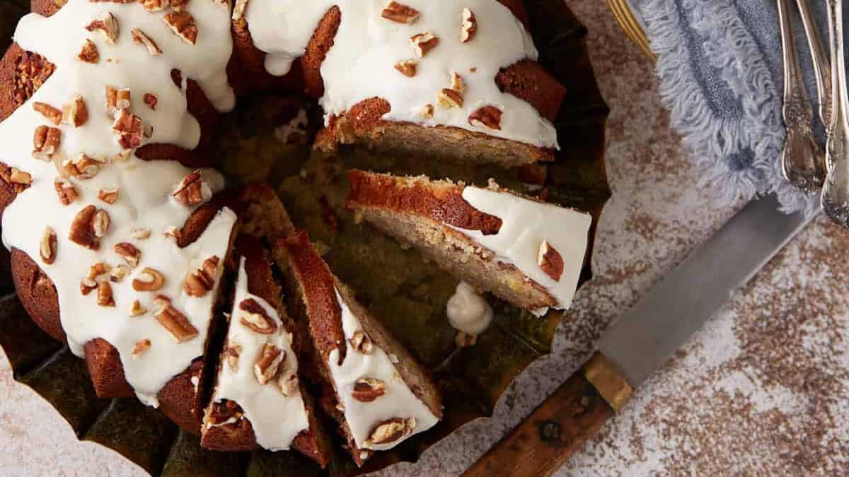 A hummingbird cake sliced next to cups of coffee.