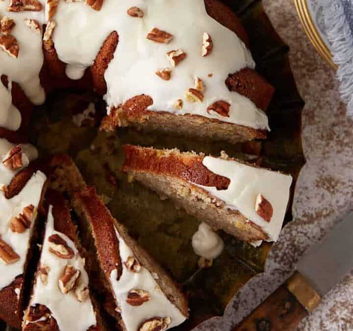 A hummingbird cake sliced next to cups of coffee.