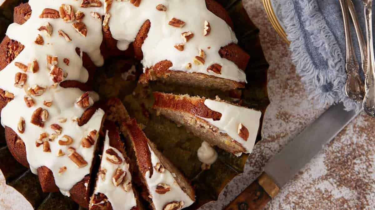 A hummingbird cake sliced next to cups of coffee.