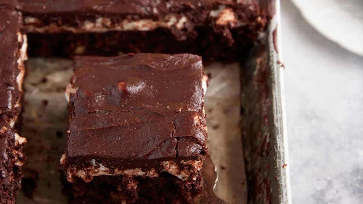 A chocolate mud cake with a piece being removed.