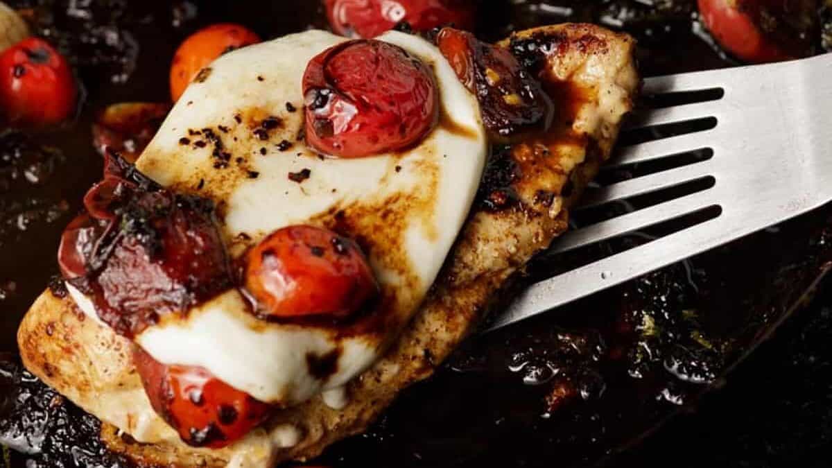 Chicken mozzarella with tomatoes in an iron skillet.