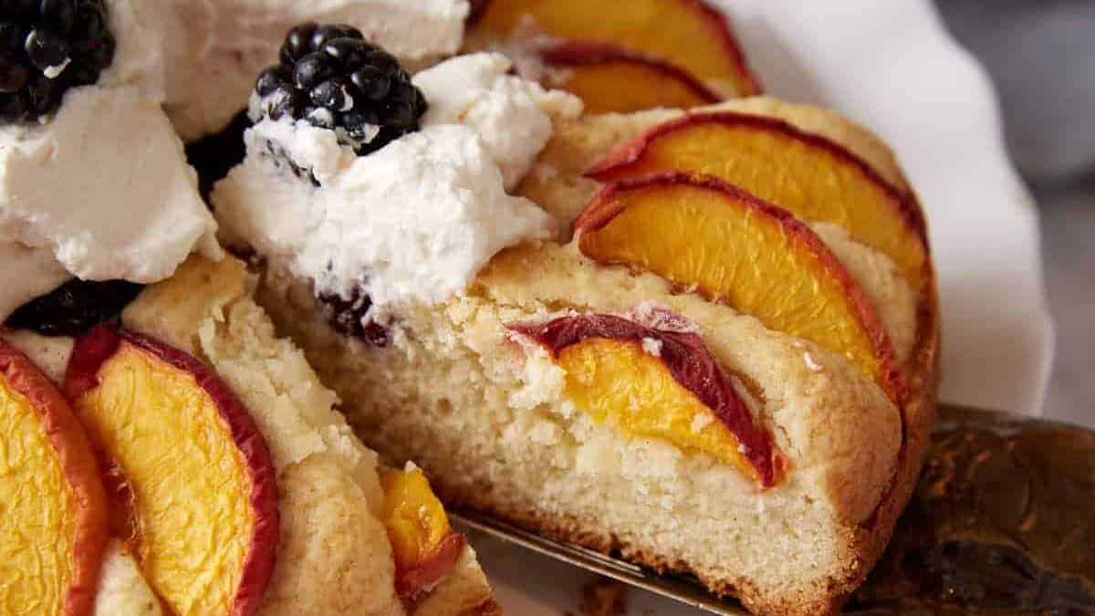 A slice of peach blackberry cake topped with whipped cream.